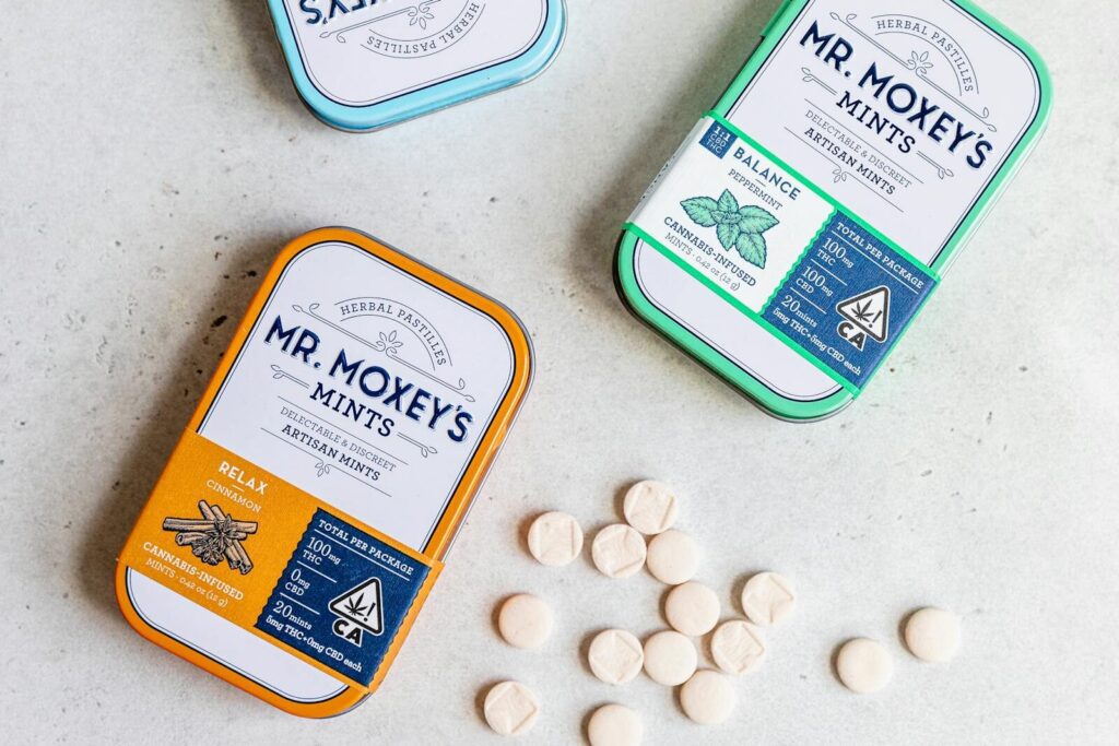 Top view of cannabis-infused artisan mints in colorful tins by Mr. Moxey's, showcasing relaxation and balance.